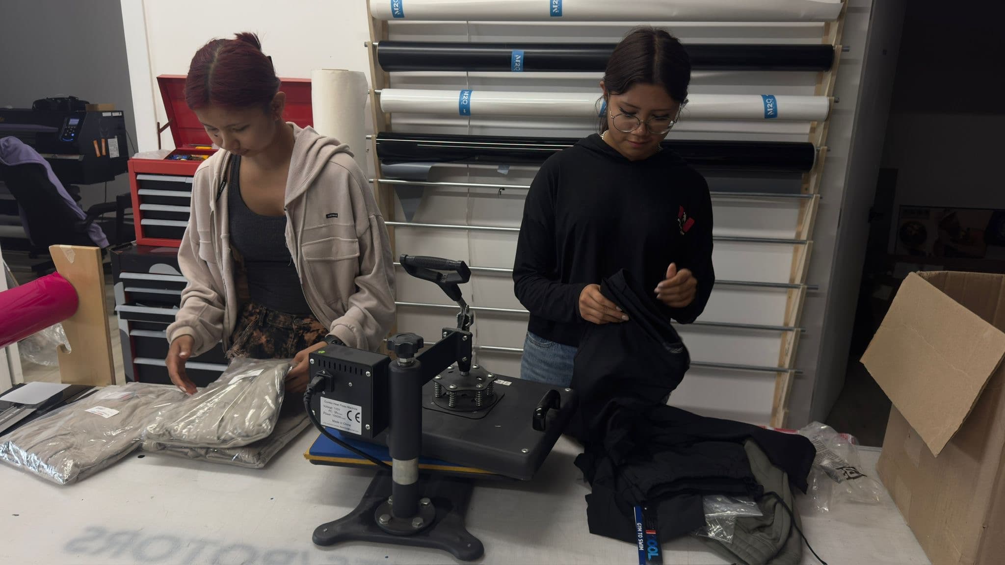 Two young people pressing printed designs onto garments with a heat press